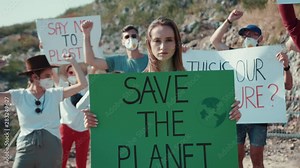 Outdoor portrait of woman activist with Save the Planet ecology poster. In background fighting people protesting against garbage pollution staying at dump in city outskirts.
