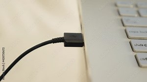 Close up of hand inserting plugging data cable into usb port in laptop, data transfer