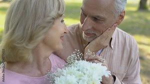 Senior man giving flowers to beloved woman, pleasant surprise, attention, care