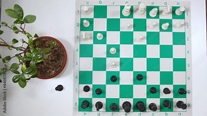 A person hand moving a horse piece up and then side ways on a chess board, static shot