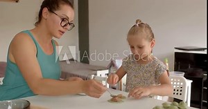 Mother daughter makes food at the table. She passes on knowledge delightful scene of a loving mother and daughter enjoying their cooking time in a cozy kitchen together