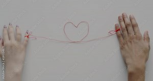Male and female hands connected with heart shape string moving apart separating on white color background. Break-up and divorce concept.