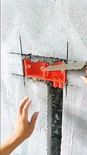 Installing red plastic electrical outlet box neatly into wall groove
