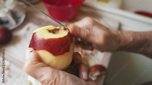 Old woman peeling apples in her kitchen at home. Homemade natural food concept.