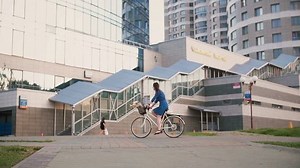 Side view of a girl in a dress with long dark hair cycling near building in the city in summer, slow mo