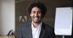 Head shot of smiling handsome Moroccan middle-aged business man in elegant formal suit posing for camera at workplace in modern office. CEO, executive manager, professional occupation person portrait