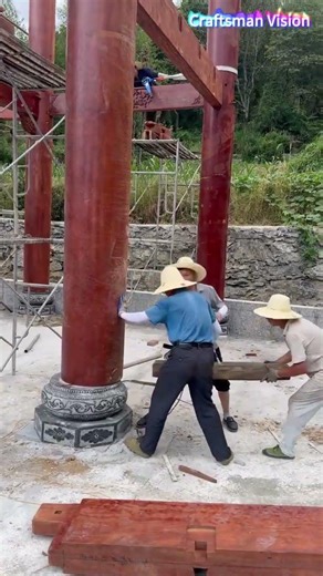 Wooden house pillar construction: Installing giant wooden pillars on stone plinths