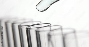 Medical laboratory test, pipette drips transparent chemicals into test tubes on white background. Chemical and medicine concept. Close-up side view.