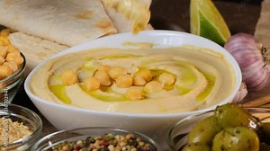 Chickpea hummus made from mashed chickpeas dip with tahini lemon garlic and olive oil close-up. Enjoying yummy hummus with pita, lavash, bread sticks, grissini. Kosher healthy vegan food. Lean dish