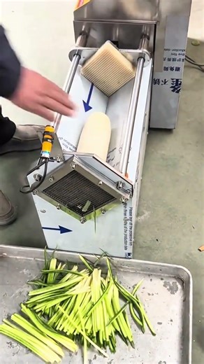 Slicing fresh cucumbers into thin strips using an automatic vegetable cutter for cooking garnish