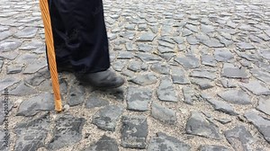 Man walking on a cobblestone road (slow filming, side view)