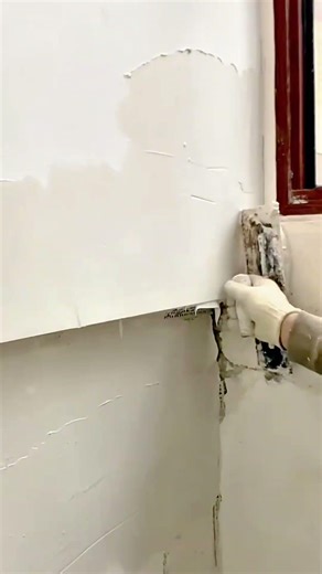 efficient interior wall plastering activity using a specialized scraper to create a smooth surface