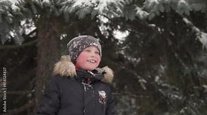 Happy child fooling around in the winter forest. The joy of the winter season in the family circle.
