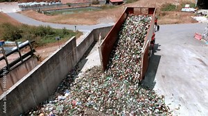 Truck is unloading glass on concrete surface in a warehouse, drone view, glass recycling in a processing center concept.