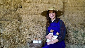 young woman, dairy farmer drink milk in cowshed. Attractive agricultural farmer people holding a bottle of milk after milking cow with happines at livestock farm industry.