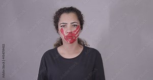 Afro woman, latin american, afro hair, serious, with red handprint on face, looking at camera serious, symbol of impotence, video prevention of violence against women, domestic violence