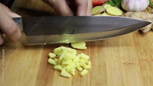 Women hand cutting organic raw ginger root slices on a wooden chopping board in the kitchen. Chop ginger.