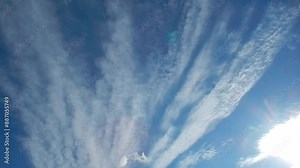 Blue sky, white clouds in the shape of rays slowly moving and sunlight - natural sunny calm background. Topics: abstraction, pattern, weather, meteorology, sky space, delicate clouds, atmosphere