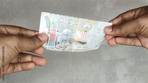 Hand checking kuwaiti dinar (kwd) currency note money for analyzing authenticity due to suspicion of forgery or counterfeit. Kuwait fake money concept. Extreme closeup macro side view.
