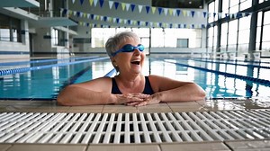 Download Joyful senior woman enjoying swimming practice in indoor pool during sunny day for free