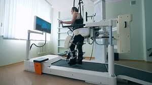 Modern medical recovery device. Training process of a physically challenged man on a walking simulation system