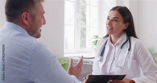 Doctor or nurse performs a medical exam for a man patient during a clinic visit. Healthcare professionals engaging in conversation and providing medical care in a clinical setting.