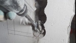 Knocking plaster off the wall.