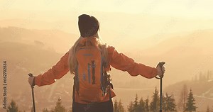 Woman hiker, hiking backpacker traveler camper walking on the top of mountain in sunny day under sun light. Beautiful mountain landscape view, nordic walking