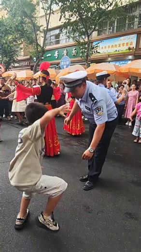 ✨🇨🇳In the streets of Xinjiang, a traffic police officer and a little boy are joyfully dancing traditional ethnic dances together. Around them, people in vibrant traditional costumes join the dance, while the crowd watches with delight.