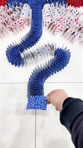 Artist Vista on Instagram: "Thousands of playing cards become a single moving canvas. This artist transforms patience, precision, and gravity into large-scale kinetic artworks where every card matters. Flowing paths, spirals, and intricate images are built card by card, only to come alive in one continuous chain reaction. The work balances control and chaos. Structure meets motion. A temporary masterpiece that exists fully only in the moment it falls. A reminder that beauty can be both fragile a