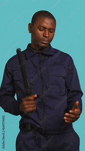 Vertical video Security guard smacking hand with baton, intimidating suspects. Portrait of bodyguard showing truncheon, threatening to subdue criminals, shaking head, studio background, camera B