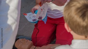 A first aid responder is taking off a sticker and she hands it over to one of the boys.
