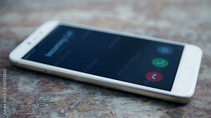 Incoming call on white mobile phone on wooden surface