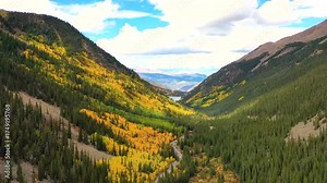 In Oregon’s Cascade Mountains, mist curls through golden forests as rugged volcanic peaks rise above clouds drifting across the cool autumn sky.