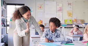 Teacher woman, high five boy and classroom with achievement, success and mentorship for learning. Education, development and students with goals, knowledge and books with celebration, school and desk