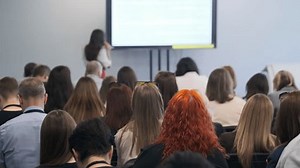 Business presentation at a tech conference featuring a large audience attentively listening to a speaker. The event demonstrates professional engagement and knowledge sharing.