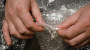 Fingers popping bubbles in bubble wrap close-up anti-stress therapy. Nervous man press plastic bubble wrap as a stress relief. man close up pressing bubble wrap with fingers from delivery packaging.