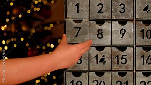 Christmas time.advent calendar. child hand opens the advent calendar near Christmas tree with glowing garland near Christmas tree with glowing garland.Gifts and surprises for Christmas and New Year.