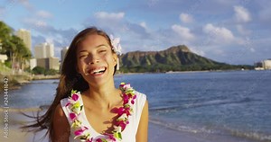 Hawaii - Beach girl smiling laughing cute, adorable and beautiful on Waikiki Beach wearing traditional flower Lei on Hawaiian beach. Multiracial Asian Caucasian girl at sunset on Oahu, Hawaii, USA