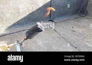 Slow motion closeup of gas heating torch producing strong flame for bitumen membrane bonding during waterproofing installation