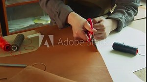 General view of the tanner's desktop, which is preparing to create designer shoes made of genuine leather. Cuts leather with scissors.