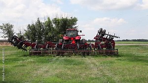 Modern tractor with towed equipment in an agricultural field demonstrating an automatic harrow