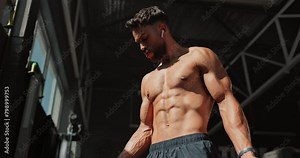 Music, dumbbell and man exercise for muscle, wellness and body health in gym. Fitness, weightlifting and strong abs of shirtless bodybuilder training with earphones for listening to serious audio