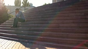 Young man sitting on stairs, problem, depression, square daytime