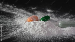 Pills fall onto white powder powder scatters concept of drug addiction and social degradation with cocaine