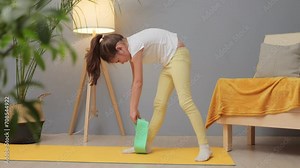 Little gymnasts at home. Children's workout session. Fun and fit childhood. Caucasian little girl with brown hair and ponytail doing sports exercises with resistance band on mat at home