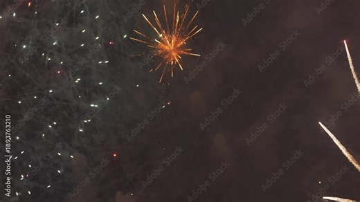 Video shows a brilliant firework explosion filling the night sky with red and gold sparks. The initial burst fades, leaving glowing embers falling through thick smoke in a beautiful,