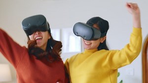 Young Asian woman dancing while using 360 VR headset for virtual reality, metaverse at home