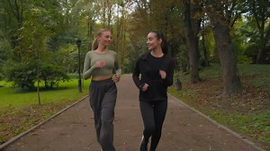 Happy women active fit sporty girls Caucasian ladies jogging running together in park outdoors two happy smiling sportswomen female joggers runners healthy lifestyle morning jog run in city outside