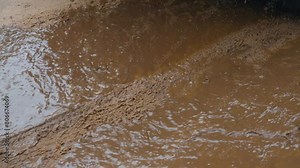Car drives through puddle, splashing water and mud in different directions. Spinning SUV tires close-up. Rotating tyre on dirty road. Automobile offroad